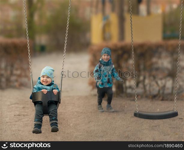 Little boy is swinging at playground, autumn