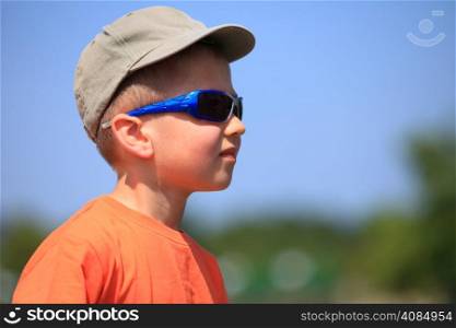 Little boy kid with sunglasses and cap outdoor sky background