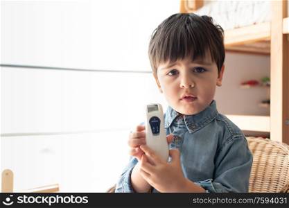 Little boy learning how to use a digital thermometer - Corona Virus 2020