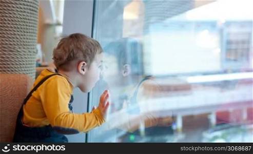 Little boy looking out the window being surprised and pointing somewhere