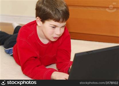 Little boy lying on the floor with portable computer