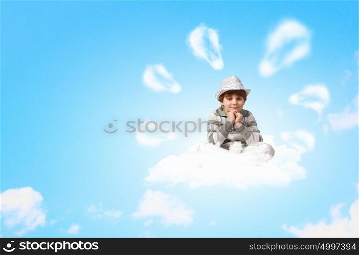 Little boy meditating. Image of little boy sitting on clouds and relaxing