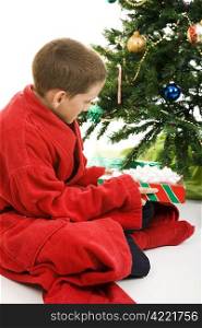 Little boy opening a Christmas present under the tree. White background.