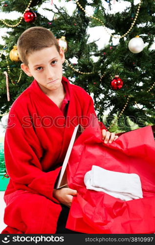 Little boy opening a wrapped present of socks on Christmas morning.