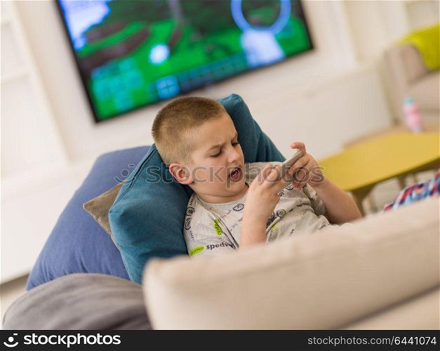 little boy playing video games on smartphone at home