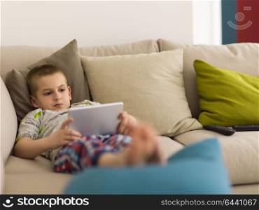 little boy playing video games on tablet computer at home