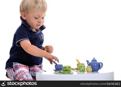 little boy playing with a doll&rsquo;s tea set