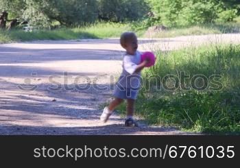 Little boy playing with ball in a summer park