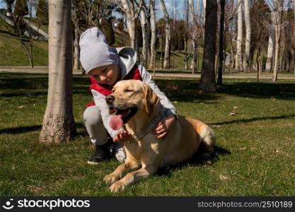 little boy playing with dog labrador in spring park. boy walking with a pet