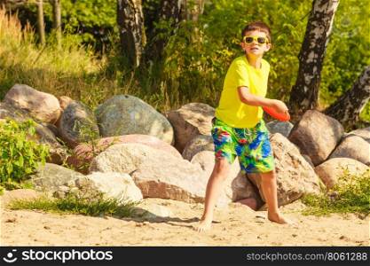 Little boy playing with frisbee disc.. Play and fun concept. Little playful enjoyable boy kid throwing frisbee disc. Male child having fun playing outdoor on beach.