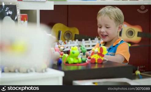 Little boy playing with toys in game room or nursery school. Children activities