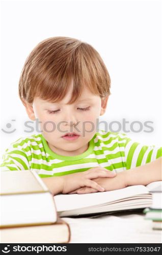 Little boy reads one of set of the books, isolated on a white background