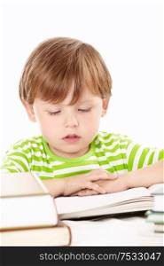 Little boy reads one of set of the books, isolated on a white background