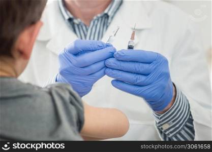 Little boy receives a vaccination in the doctors office.