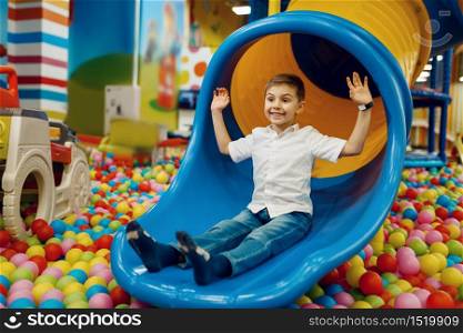 Little boy ride down the hill in the entertainment center. Male child leisures on holidays, childhood happiness, happy kid on playground. Boy ride down the hill, entertainment center