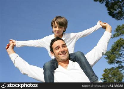 Little boy riding on his father&rsquo;s shoulders