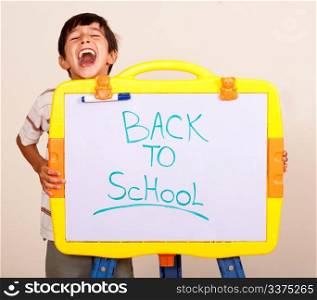 Little boy screaming with a whitebaord with text back to school on it