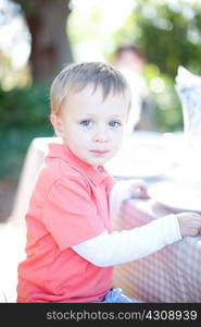 Little boy sitting at table outdoors