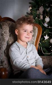 Little boy sitting by Christmas tree. Happy child, Christmas celebration. Little boy sitting by Christmas tree. Happy child, Christmas celebration.