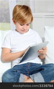 Little boy sitting in sofa with electronic tablet