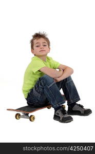 little boy sitting on his skateboard