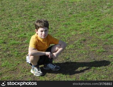 Little boy sitting upset on a soccer field after losing a game