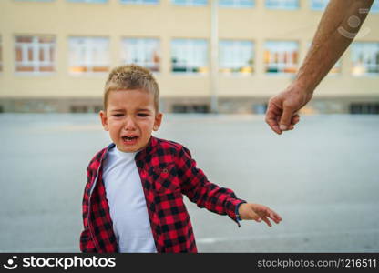 Little boy small child in red shirt crying while some man is trying to reach him