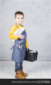 little boy standing with tool box paper rolls