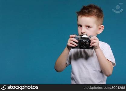 Little boy taking a picture using a retro camera. Child boy with vintage photo camera isolated on blue background. Old technology concept with copy space. Child learning photography .. Little boy taking a picture using a retro camera. Child boy with vintage photo camera isolated on blue background. Old technology concept with copy space. Child learning photography