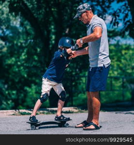 Little boy trying snakeboard with grandpa