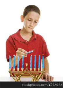 Little boy uses the shamash candle to light the menorah. Isolated on white.