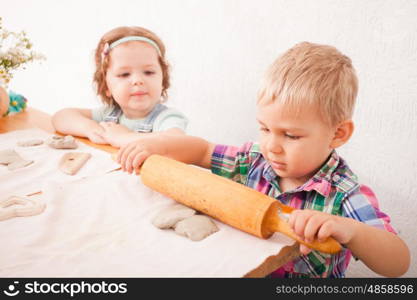 Little boy using a rolling pin that to roll modelling clay. The art with plasticine