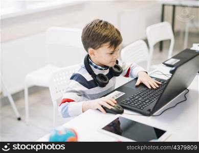 little boy using laptop desk classroom