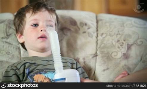 Little boy using nebulizer to inhale medicine, close up