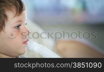 Little boy using nebulizer to inhale medicine, close up side view