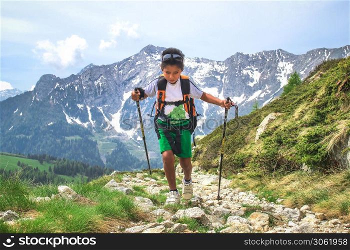 Little boy walks during an excursion on mountain trail with the backpack