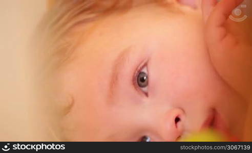 Little boy watching a film lying in the playpen. Closeup.