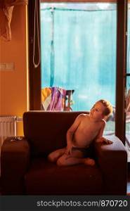 Little boy watching a movie sitting in a armchair at home. Candid people, real moments, authentic situations