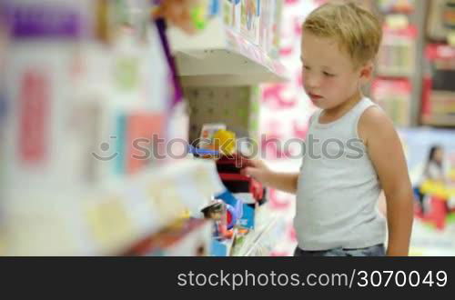 Little boy watching and touching toys in the shop