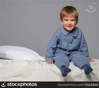 Little boy wearing blue pyjamas in bed