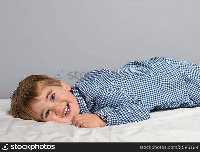 Little boy wearing blue pyjamas in bed