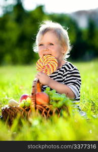 little boy with a sweet on a green grass