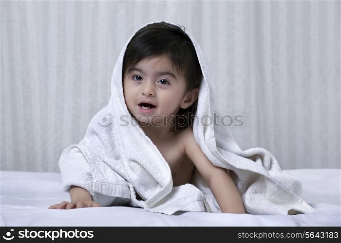 Little boy with a towel around his body on a bed