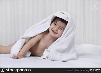 Little boy with a towel on his head on a bed