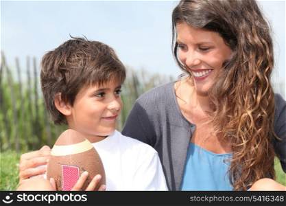 little boy with American football sat with mother