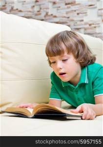 Little boy with book on sofa