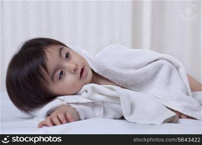 Little boy wrapped in a towel on a bed