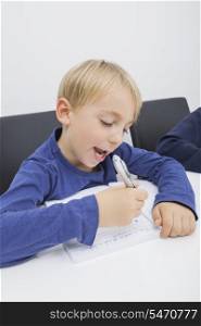 Little boy writing in book at table
