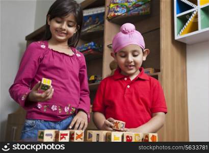 Little brother and sister playing with wooden toy blocks