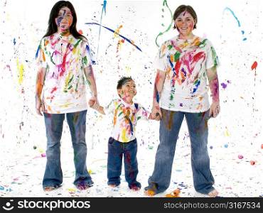 Little brother and teen sisters standing in paint mess, holding hands. Ages 4, 13, 14.